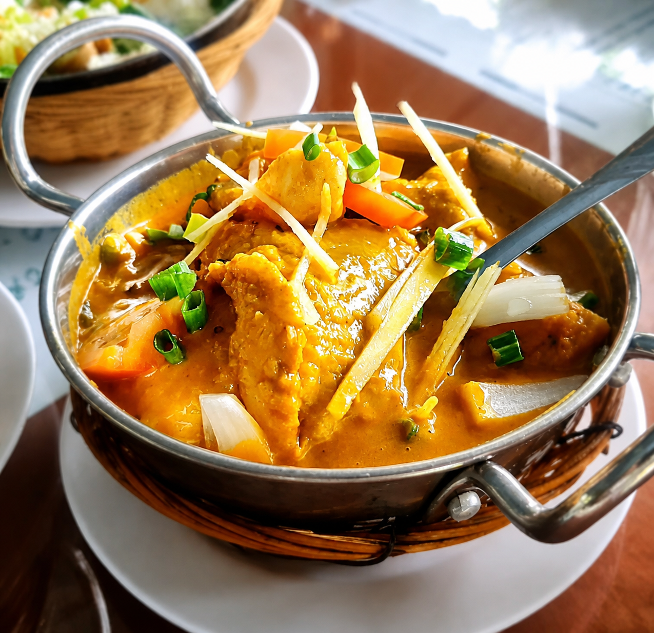 A golden turmeric curry with cauliflower, carrot and onion in a karahi.