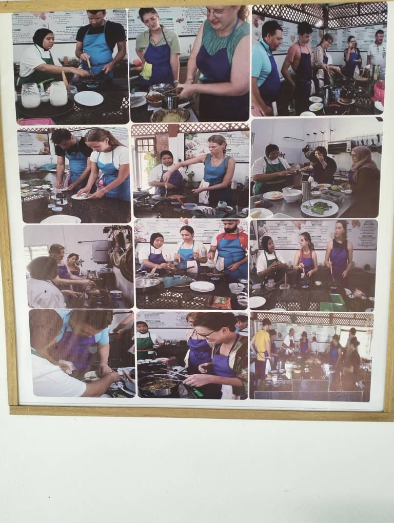 The restaurant's own framed wall of photographs from past cooking classes, showing participants in aprons chopping and cooking.