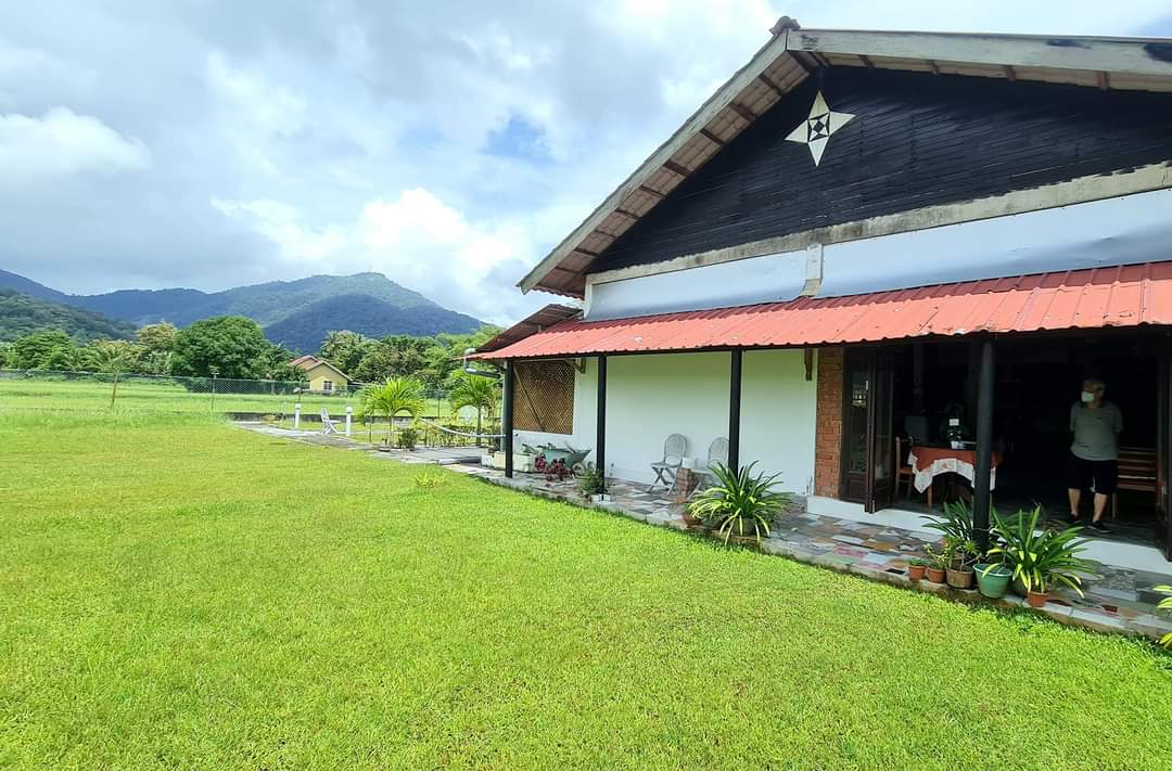 The restaurant building seen across its own lawn on a bright day, with hills behind it.